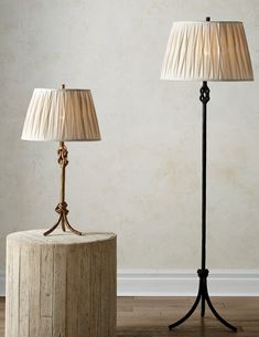 two lamps sitting next to each other on top of a wooden table in front of a wall