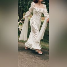 a woman in a white dress is walking down the street