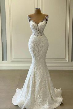 a white wedding dress on a mannequin in front of a wall and floor