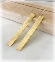 "These beautiful bar earrings are hand forged and hammered to shimmer and sparkle! Keep the eyes on you with these minimal yet statement earrings! Wear them with your dress or with your jeans! They match with every colour and will add class to every outfit!  The ear wires are 24k gold plated sterling silver and the bars are solid brass. They measure approx. 7-8 cm / 2.7\".  SENDING AS A GIFT? All orders come ready for offering as gifts. They are carefully wrapped with beautiful ribbon in kraft gift boxes along with a card with care instructions. The items can be sent directly to your gift recipients by writing their address at checkout. A gifting card can be added to their gift. OUR SHOP https://www.etsy.com/shop/KarousosJewelry/ ~ When you shine... We smile! ~" Modern Hammered Linear Earrings For Gift, Modern Hammered Linear Earrings As Gift, Minimalist Hammered Dangle Earrings, Handmade Gold Linear Earrings For Everyday, Gold Hammered Metal Linear Earrings, Minimalist Hammered Dangle Linear Earrings, Matte Gold Hammered Earrings For Gift, Matte Gold Hammered Earrings As Gift, Gold Hammered Drop Linear Earrings