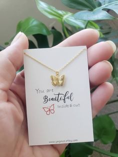 a small gold butterfly necklace on a card