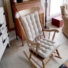 a rocking chair in a living room next to a dresser and couch with pillows on it