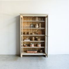 a wooden cabinet filled with lots of pots and pans on top of shelves next to a wall