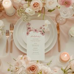 the table is set with pink and white flowers, silverware, and menu cards