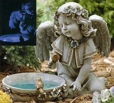 an angel figurine sitting on the ground next to a bird bath