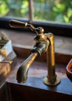 a brass faucet in front of a window