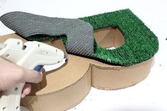 someone is using glue to cut grass into the shape of a golf ball and put it in a cardboard box