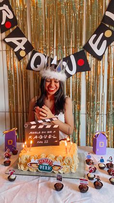 a woman wearing a birthday hat standing in front of a cake