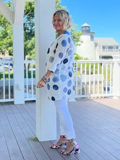 a woman standing on a porch wearing white and blue polka dots