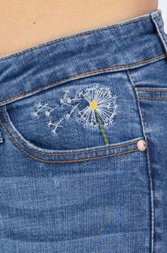 a woman's stomach with a dandelion embroidered on the back of her jeans