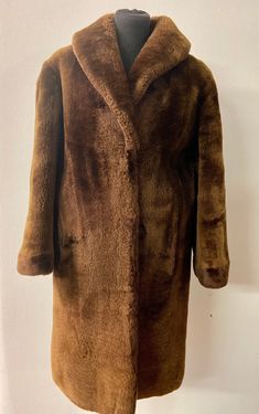 Stay cozy and chic this winter with our vintage brown shearling coat. This knee-length winter coat is not only stylish but also incredibly warm, making it the perfect addition to your cold-weather wardrobe. It boasts a luxurious texture that is both soft and durable. With its timeless design, this coat is sure to become your go-to for staying fashionably warm all season long. Hurry and grab this must-have warm winter coat before it's gone! Vintage items do not always have labels and the sizes va Brown Fur Coat With Faux Fur Lining, Vintage Brown Outerwear With Faux Fur Trim, Classic Brown Faux Fur Outerwear, Vintage Long Coat In Faux Fur, Vintage Brown Faux Fur Outerwear, Vintage Faux Fur Coat For Cold Weather, Brown Vintage Fur Coat With Faux Fur Trim, Classic Brown Fur Coat With Faux Fur Trim, Brown Fitted Fur Coat For Cold Weather