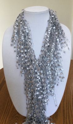 A beautiful and unique handmade accessory that shimmers and portrays a beaded look! Each Fringed Scarf Necklace is handmade and can be worn multiple ways. Item is lite weight and is available in many stunning great colors. Comes packaged in an organza bag. A great gift item. Fringed Scarf Necklace is approx. 66 inches in length and is made of 97% Nylon and 3% Lurex. Handwash in cold water and lay flat to dry. Each item is made by hand and slight variations may occur. Silver Faceted Beads Necklace For Party, Silver Beaded Long Necklace For Celebration, Silver Long Beaded Necklace For Celebration, Handmade Silver Beaded Necklaces For Party, Silver Multi-strand Beaded Necklace For Party, Silver Long Beaded Necklaces For Party, Silver Necklace With Colorful Beads For Party, Silver Long Beaded Necklace For Party, Party Silver Necklace With Colorful Beads