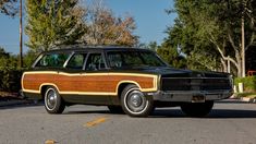 an old station wagon with wood trim parked in a parking lot next to some trees