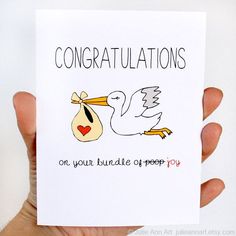 a hand holding up a card with a stork carrying a baby