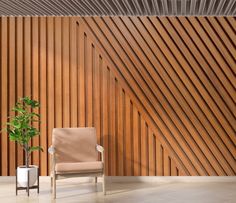 a chair next to a potted plant in front of a wooden wall