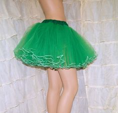 a woman's green skirt with ruffles and lace on the bottom is standing in front of a white backdrop