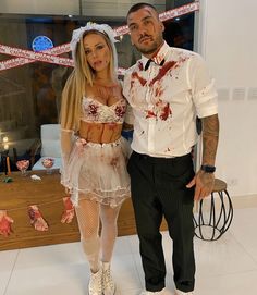 a man and woman dressed up as zombies for halloween costume party, standing next to each other