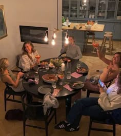 four people sitting around a table with food and drinks in front of them at night