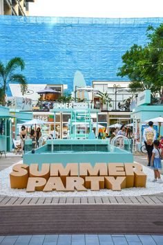 a sign that says summer party in front of a building with people walking around it