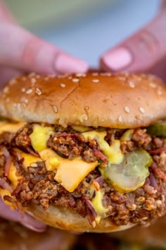 a person holding up a cheeseburger in their hands