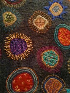 a close up view of an embroidered cloth with many different colors and designs on it