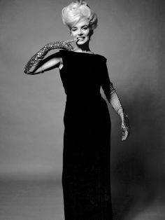 an old photo of a woman in a black dress holding a snake on her arm