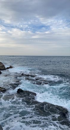 the ocean waves are crashing against the rocks