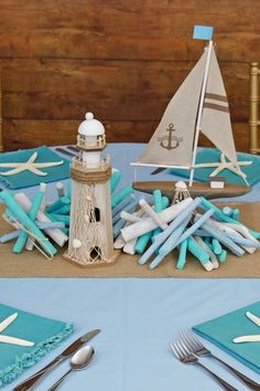 a table topped with blue and white napkins next to a light house on top of a wooden wall