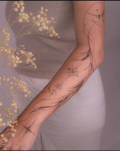 a woman's arm with tattoos on it and flowers in the foreground next to her