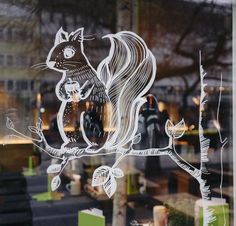 a glass window with a drawing of a squirrel sitting on a tree branch in front of it