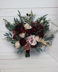 a bouquet of flowers sitting on top of a wooden bench next to a white wall