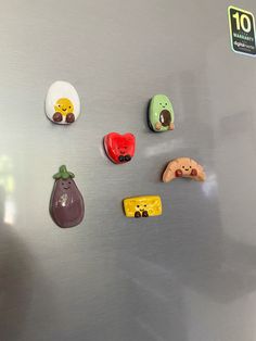 several magnets are placed on the side of a stainless steel refrigerator, which is decorated with fruit and vegetables