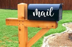 a mailbox sitting on top of a wooden post in front of a grass covered yard