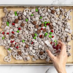 a person holding a wine glass in front of a tray full of candy and pretzels