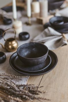 a table topped with black dishes and candles