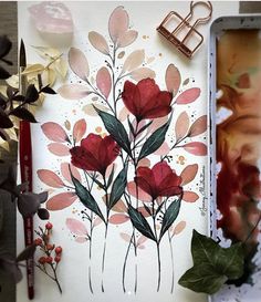 a painting with flowers on it next to some paintbrushes and other art supplies