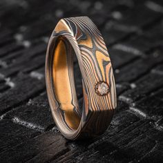 "This unique and modern feeling Mokume Gane ring is shown in the Twist pattern and the Firestorm metal combination, with a flat profile and an added flush set cognac diamond. This ring is made in a soft square shape for a unique style that still feels comfortable on the hand! Our Firestorm palette features 14k Red Gold, 14k Yellow Gold, Palladium, and Sterling Silver.  *Price does NOT include stones or setting fees* Pattern: Twist Palette: Firestorm Finish: Etched & Oxidized Profile: Flat Width Shown: 6mm Size Shown: 8.5 Stone: 3mm Cognac Diamond Price as shown for this width and ring size! If you are interested in this design please inquire for an accurate quote! We care about customer service and would like to hear from you! Please contact us to help create your treasured item, we take y Modern Brown Rings For Anniversary, Modern Brown Anniversary Ring, Modern Brown Rings For Gifts, Modern Brown Rings For Gift, Modern Brown Ring Jewelry, Luxury Brown Ring For Gift, Modern Brown Jewelry For Anniversary, Luxury Brown Rings For Gift, Luxury Brown Rings As Gifts