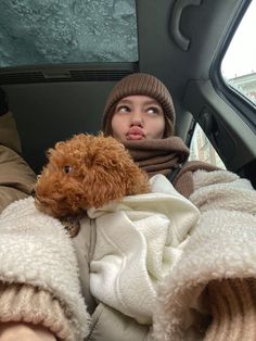 a woman sitting in the back seat of a car holding a dog