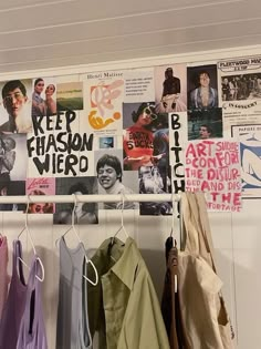 there are many posters on the wall and clothes hanging from hooks in this room,