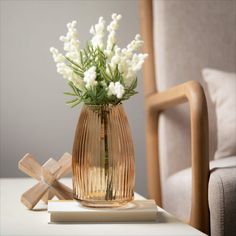 a vase filled with white flowers sitting on top of a table next to a wooden cross