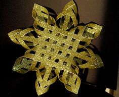 a gold paper snowflake sitting on top of a black table next to a wall