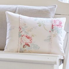 a white chair with two pillows on top of it and a pillow in the back