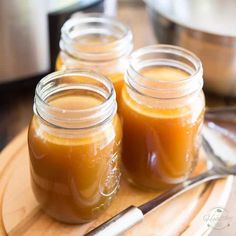 three jars filled with liquid sitting on top of a wooden cutting board