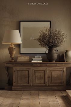 a table with vases and books on it in front of a wall mounted poster