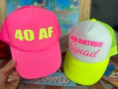 two pink and yellow hats with the words 40 af on them sitting next to each other