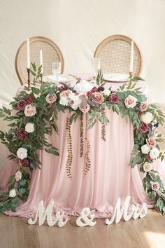 the table is decorated with pink and white flowers, greenery and mr and mrs signs