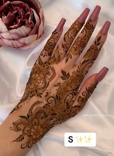 henna tattoo on hand with flower and peonye in the foreground next to it