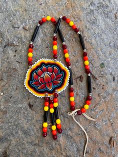 a beaded necklace with an orange flower on it sitting on top of a rock