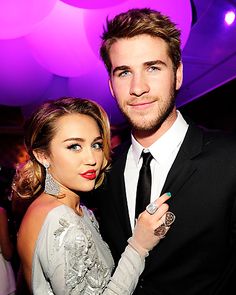 a man and woman standing next to each other in front of purple lights at an event