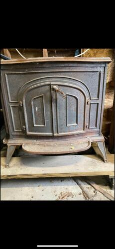 an old wood stove sitting on top of a wooden pallet